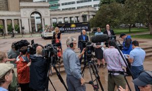 Image of The Colorado Sun gathering for a press conference surrounded by reporters.