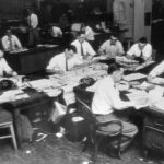 Black and white image of white men in dress shirts and ties working in the Kansas City star newsroom.