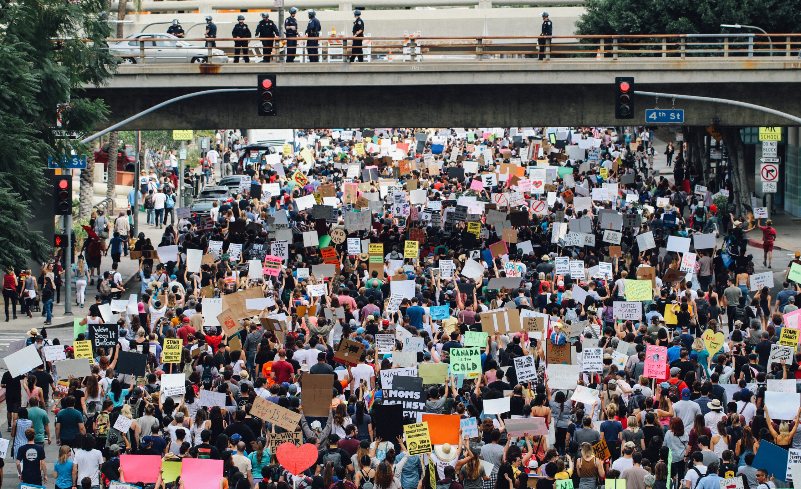 Image of crown protesting in Los Angeles. The crowd passes under a bridge where police watch the crowd from above.